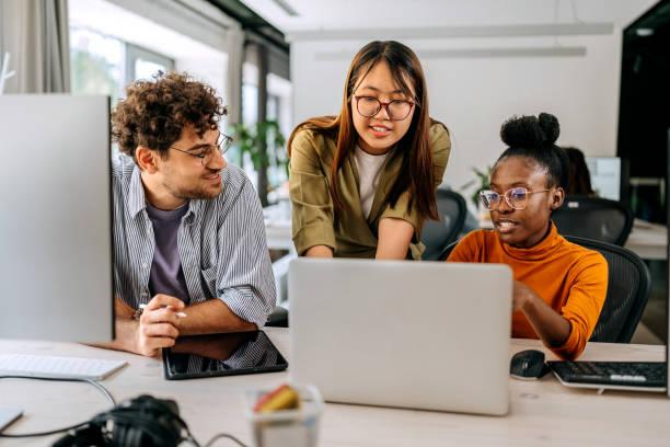Three Young Colleagues Discussing Work At Modern Office